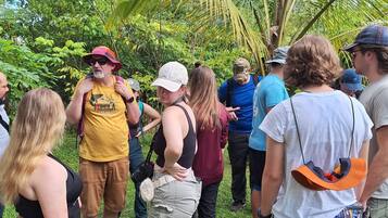 A group of people standing outdoors in a natural setting with greenery and palm trees.