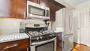 A kitchen with a stainless steel stove, oven, microwave, and refrigerator.