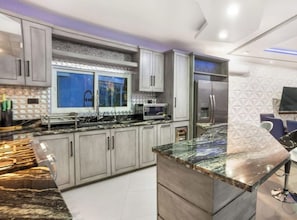 Una cocina moderna con encimeras de granito, electrodomésticos de acero inoxidable y una ventana con vistas.