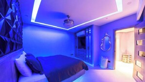 Un dormitorio moderno con una cama, un lámpara en el techo y una puerta que da a otra habitación.