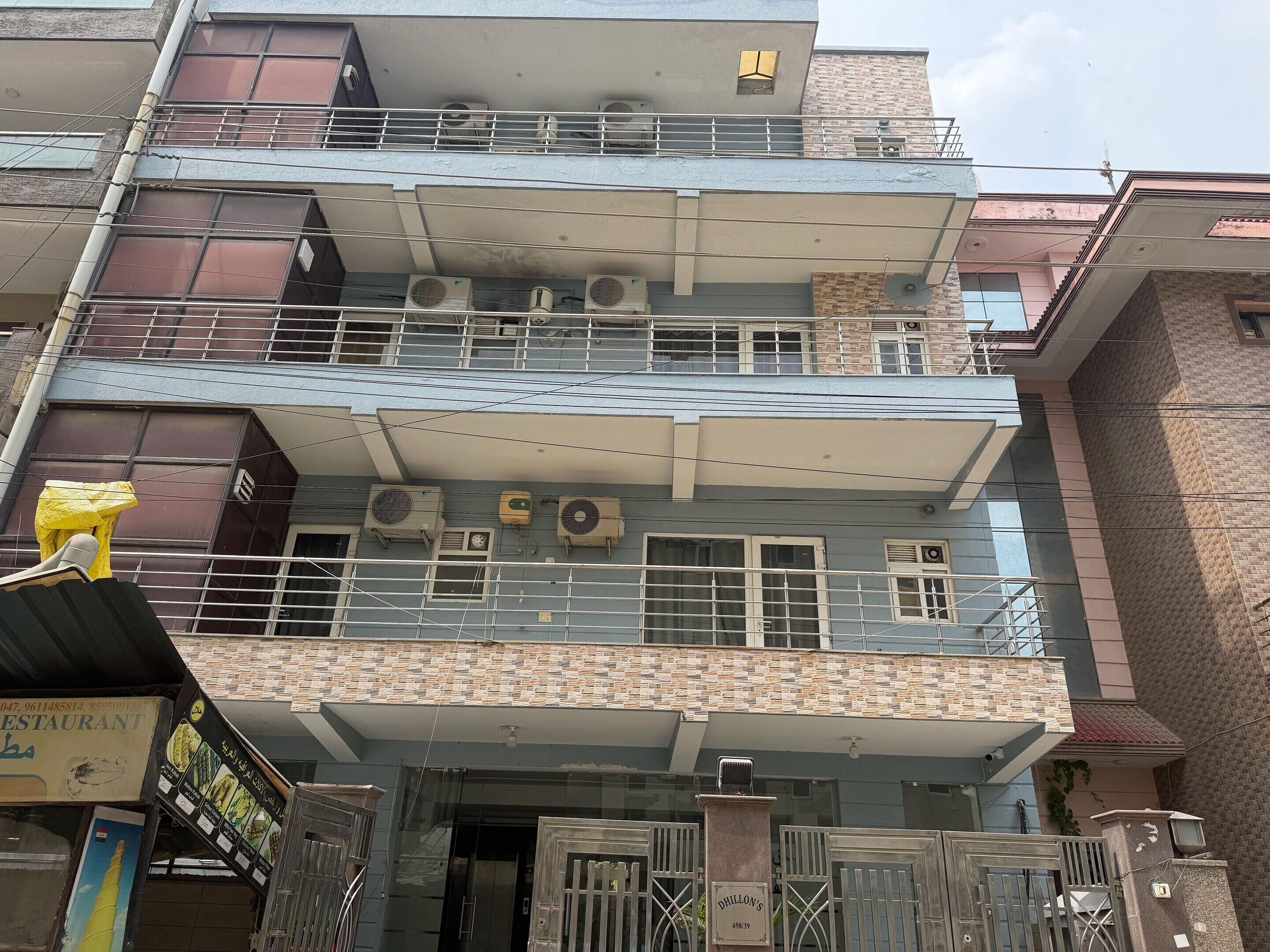 A multi-story building with balconies, air conditioning units, and a gated entrance.