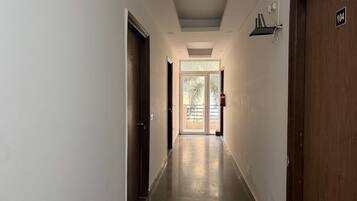 A corridor with doors on both sides, a fire extinguisher mounted on the wall, and a door with the number 104.