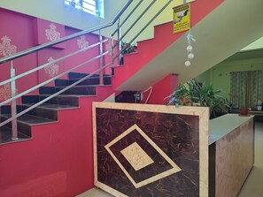 A staircase with a metal railing, a marble-patterned wall, and a warning sign about CCTV surveillance. - Classic Murshidabad Junction (Lalbag)
