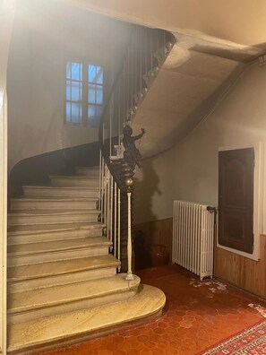 Eine Treppe mit Geländer, einem Heizkörper und einem Fenster.