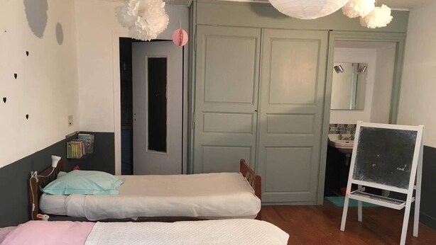 Una habitación con dos camas individuales, un armario de madera, un espejo y una pizarra sobre un atril.