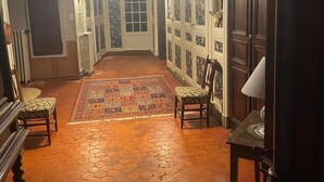 Un pasillo con alfombra estampada, muebles de madera y una puerta con paneles de vidrio.
