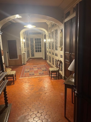 A hallway with a patterned rug, wooden furniture, and a door with glass panels.