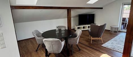 Un interior moderno con comedor, televisor de pantalla plana y tragaluz.