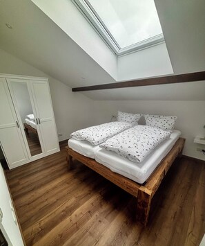 A bedroom with a skylight, wooden floor, and a bed with floral bedding.
