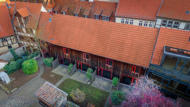 Un patio con un edificio de techo rojo, rodeado de vegetación y un pequeño jardín.
