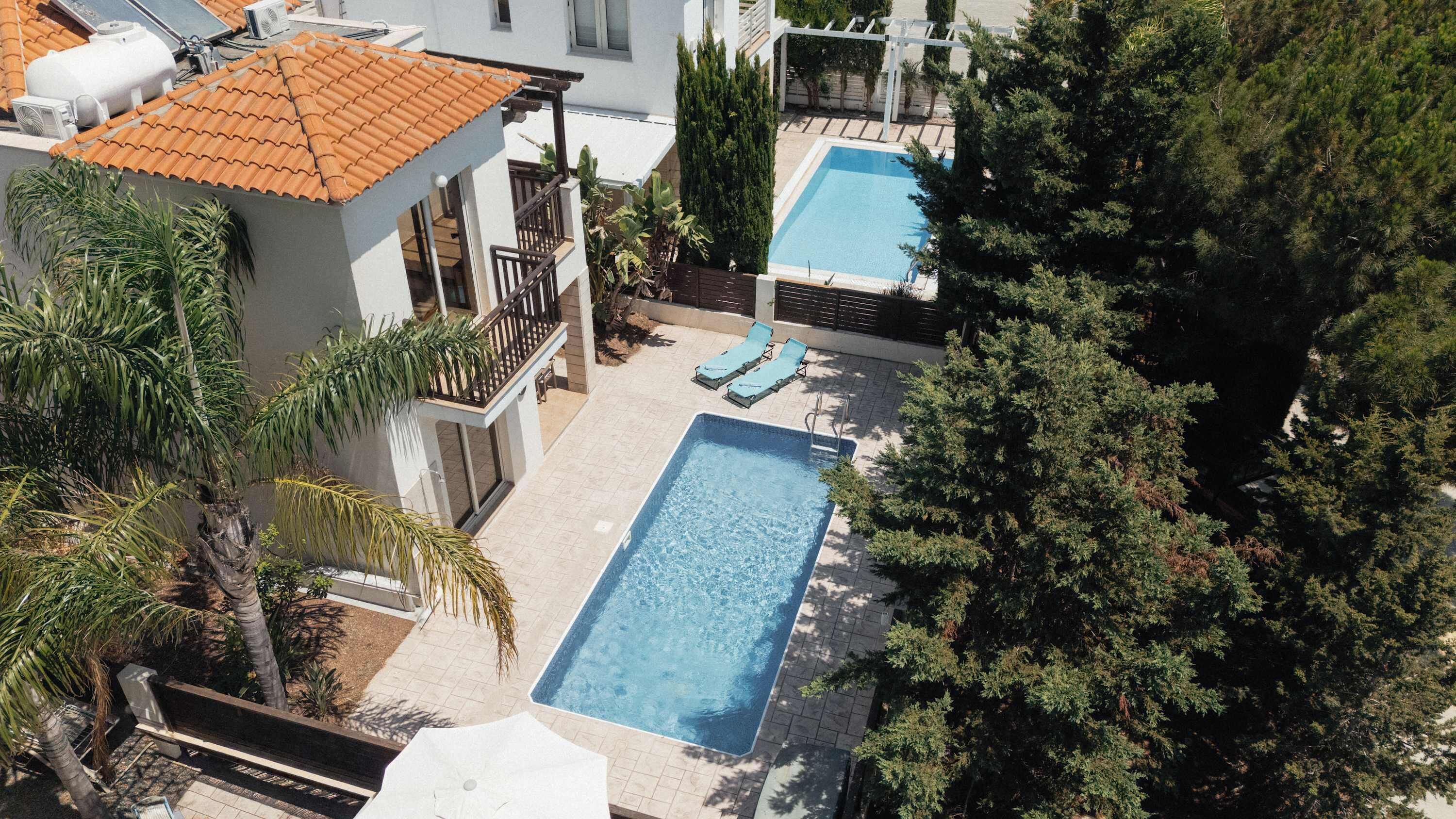 Il s’agit d’une propriété résidentielle dotée d’une piscine, de deux chaises longues et d’un patio couvert.