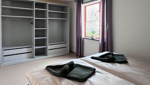 A bedroom with two beds, a wardrobe, and a window with curtains. - Elementa City Lodge Quedlinburg 2 (Quedlinburg)