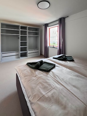 Ein Schlafzimmer mit zwei Betten, einem Kleiderschrank und einem Fenster mit Vorhängen.