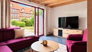 Een moderne woonkamer met een houten plafond, een grote televisie, een bank en een salontafel.