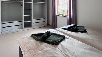 Ein Schlafzimmer mit zwei Betten, einem Kleiderschrank und einem Fenster mit Vorhängen.