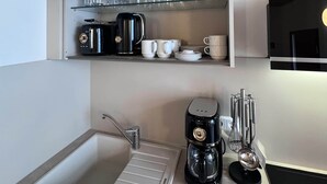 Een moderne keuken met een ingebouwde gootsteen, een koffiezetapparaat en een magnetron.