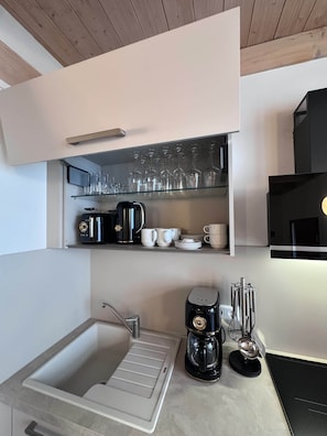 A modern kitchen with a built-in sink, a coffee maker, and a microwave. - Elementa City Lodge Quedlinburg 4 (Quedlinburg)