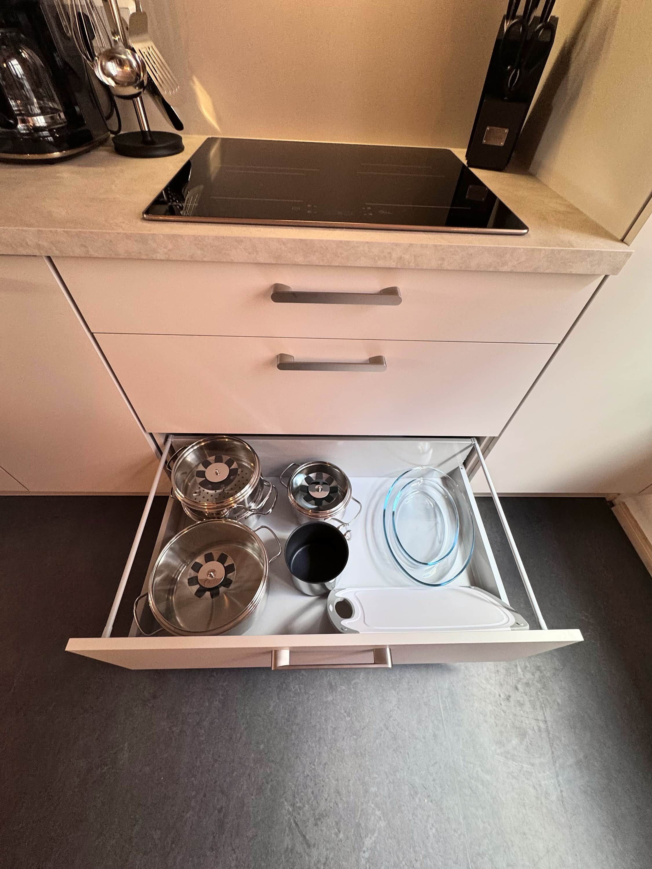 Eine Küchenschublade mit Töpfen, Pfannen und einer Glaskugel.