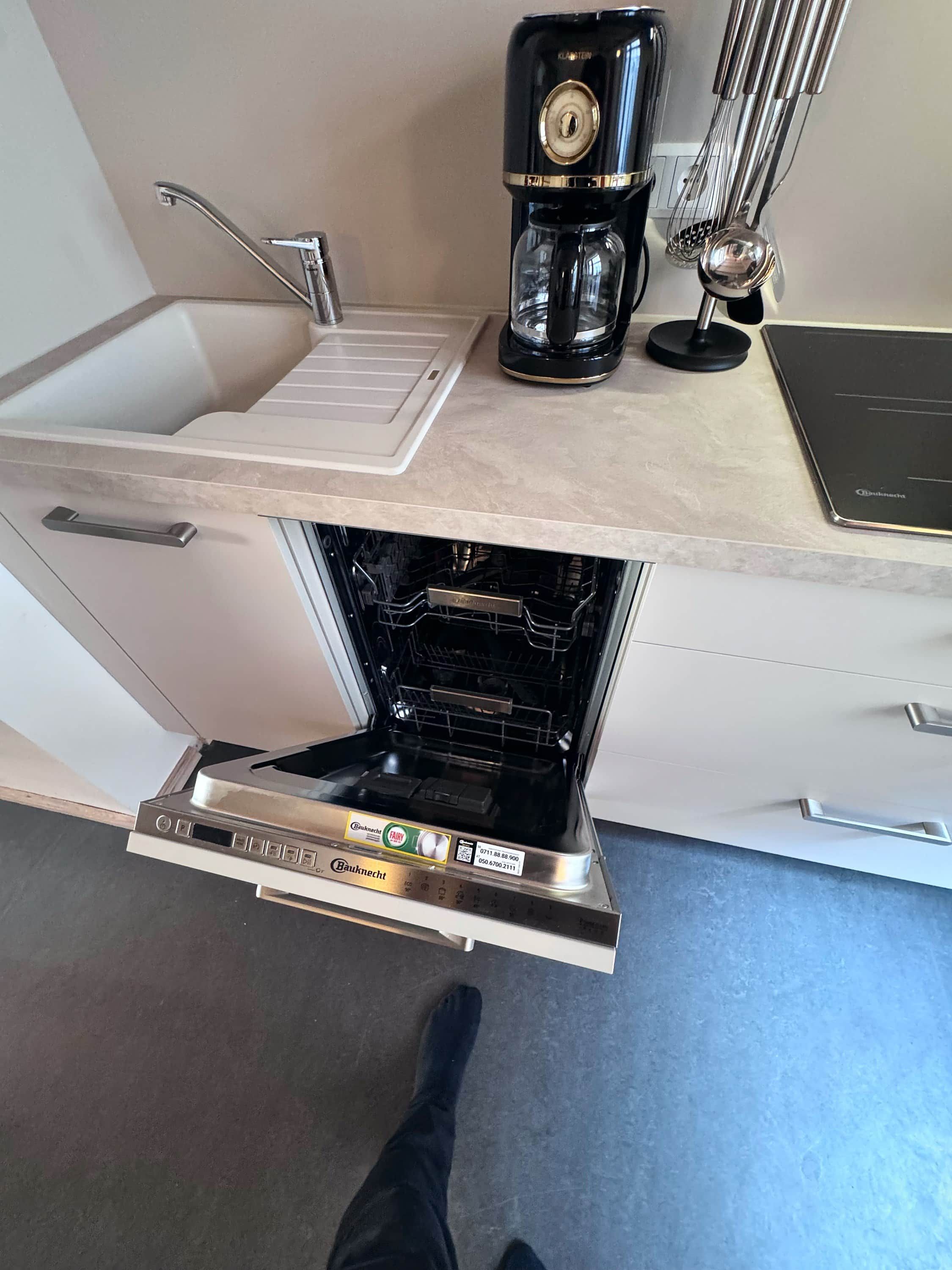 A kitchen with a built-in oven, a coffee maker, and a kettle on the countertop.