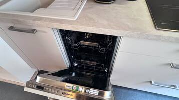 A kitchen with a built-in oven, a coffee maker, and a kettle on the countertop.