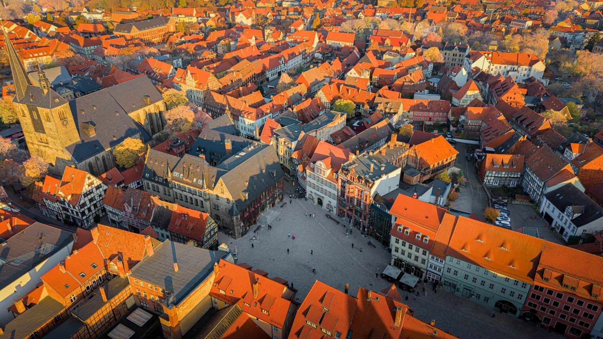 Eine Vogelperspektive einer historischen Stadt mit traditioneller Architektur, einem zentralen Platz und einer markanten Kirche.