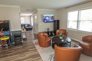 Una sala de estar con televisor, sillones de cuero, una mesita de centro y una planta pequeña.