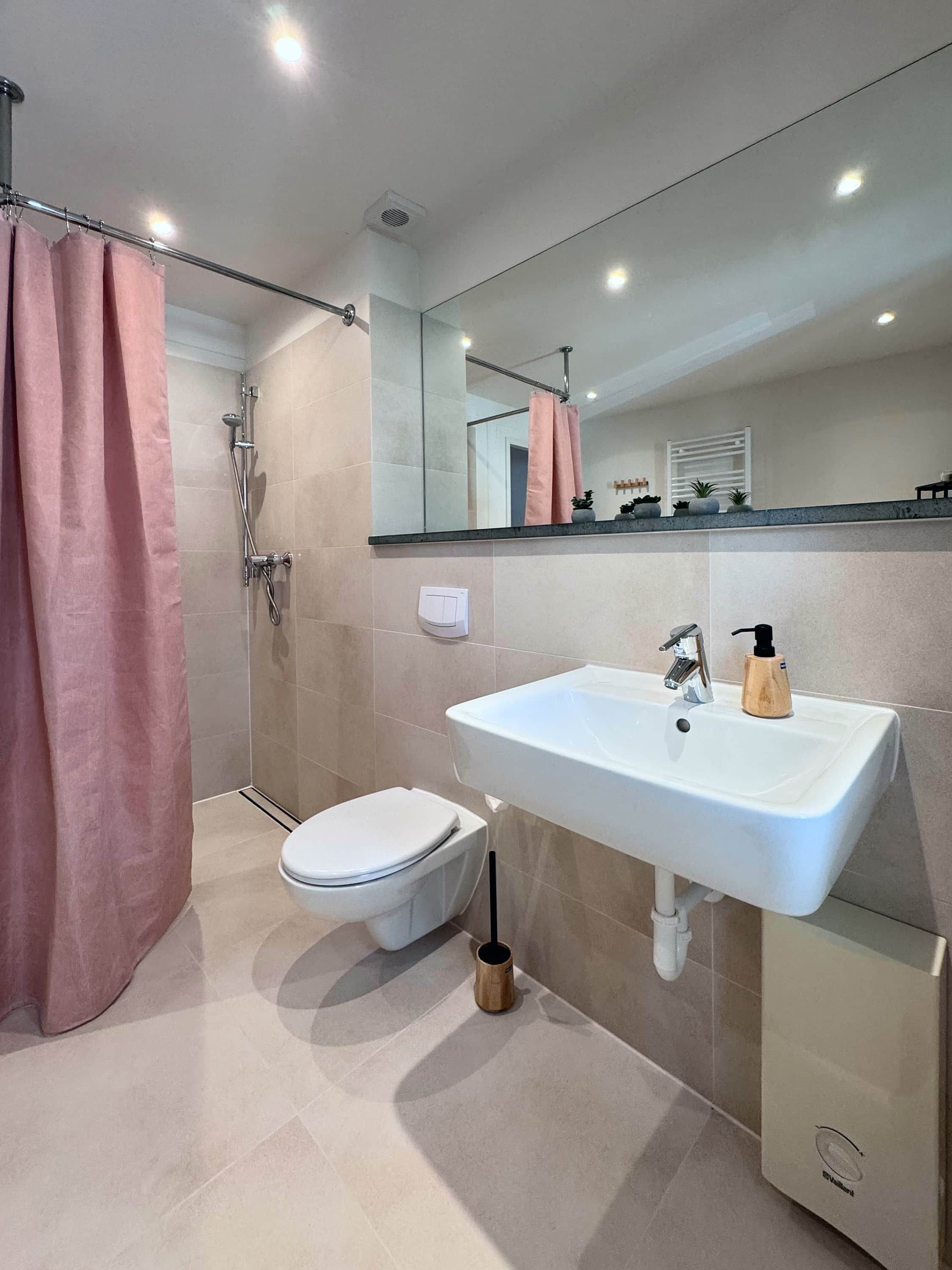 Ein modernes Badezimmer mit Dusche, Toilette, Waschbecken und Spiegel.