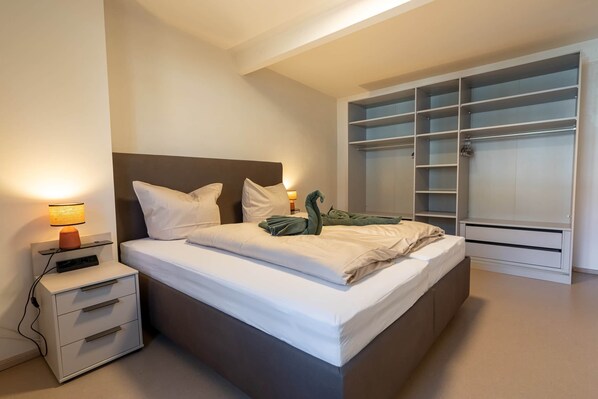 A modern bedroom with a bed, bedside tables, a lamp, and a built-in wardrobe.