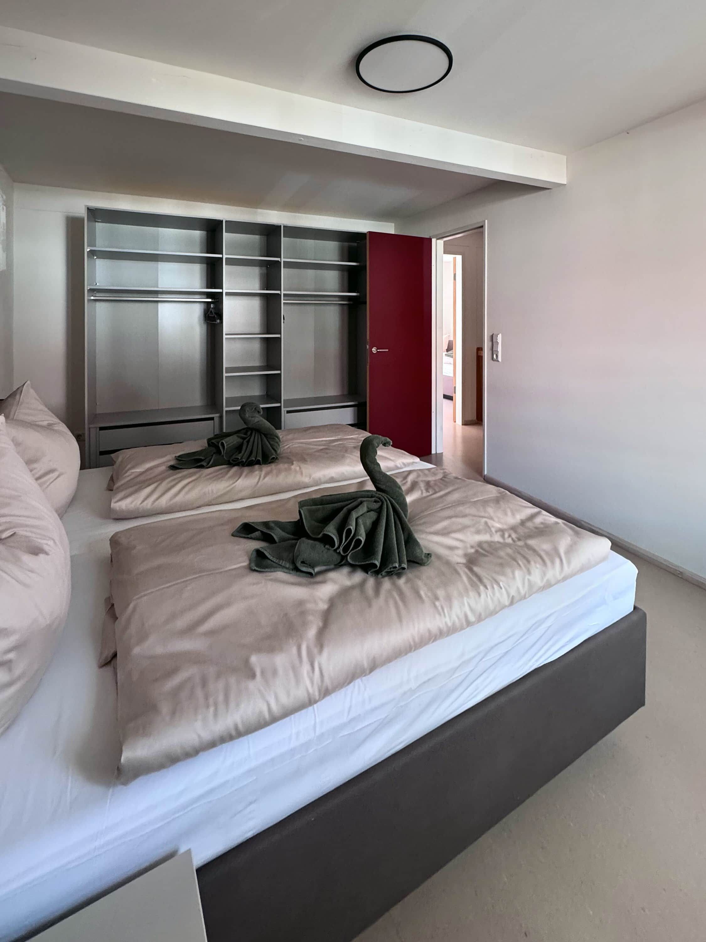 Een slaapkamer met een groot bed, een kledingkast en een rode deur.