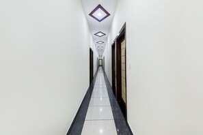 A corridor with a tiled floor, white walls, and a door on the right.