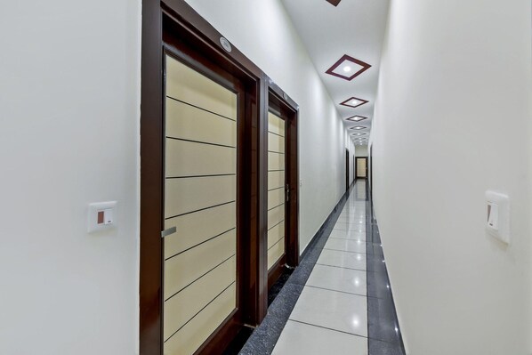 A corridor with doors, a tiled floor, and recessed lighting.