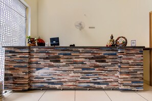 A reception desk with a rustic wood panel design, a computer monitor, and a no-smoking sign.