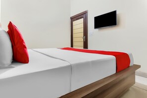 A hotel room with a bed, a television mounted on the wall, and a door with a handle.