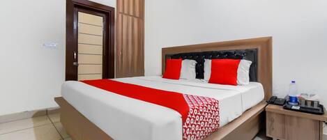 A hotel room with a bed, a bedside table, a water bottle, and a phone.