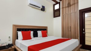 Et hotelværelse med seng, garderobeskab, natbord og aircondition.