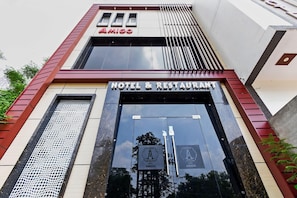 A hotel entrance with a sign reading 'AMIGO HOTEL & RESTAURANT' and a logo with a stylized 'A'.