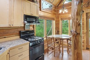 A kitchen with wooden cabinets, a stove, and a dining table with chairs.