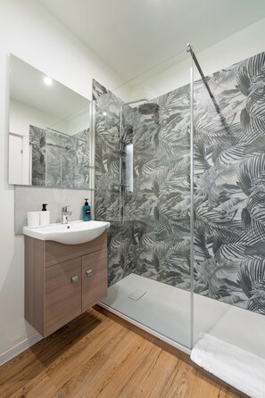 A bathroom with a glass shower enclosure, a wooden vanity, and a mirror. - Musart Green Room (Firenze)