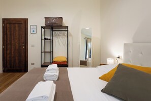 Una camera d'albergo con un letto, un armadio, uno specchio e un comodino.