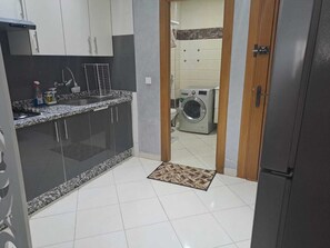 A kitchen with a washing machine and a refrigerator. - Lovely 2-bedroom apartment in Tanger near vibrant city spots (Tanger)