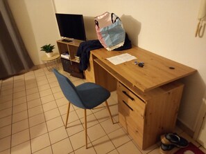A small room with a wooden desk, a chair, a television, a small plant, and a pair of shoes. - Separate entrance. Enjoy a pleasant and functional studio apartment in Niort, (Niort)