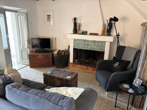 Ein Wohnzimmer mit Kamin, Fernseher und einer Couch.