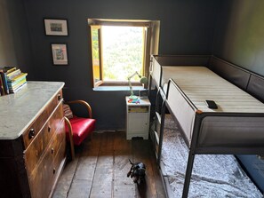 Une petite pièce comprenant un lit, un bureau, une chaise et une fenêtre.