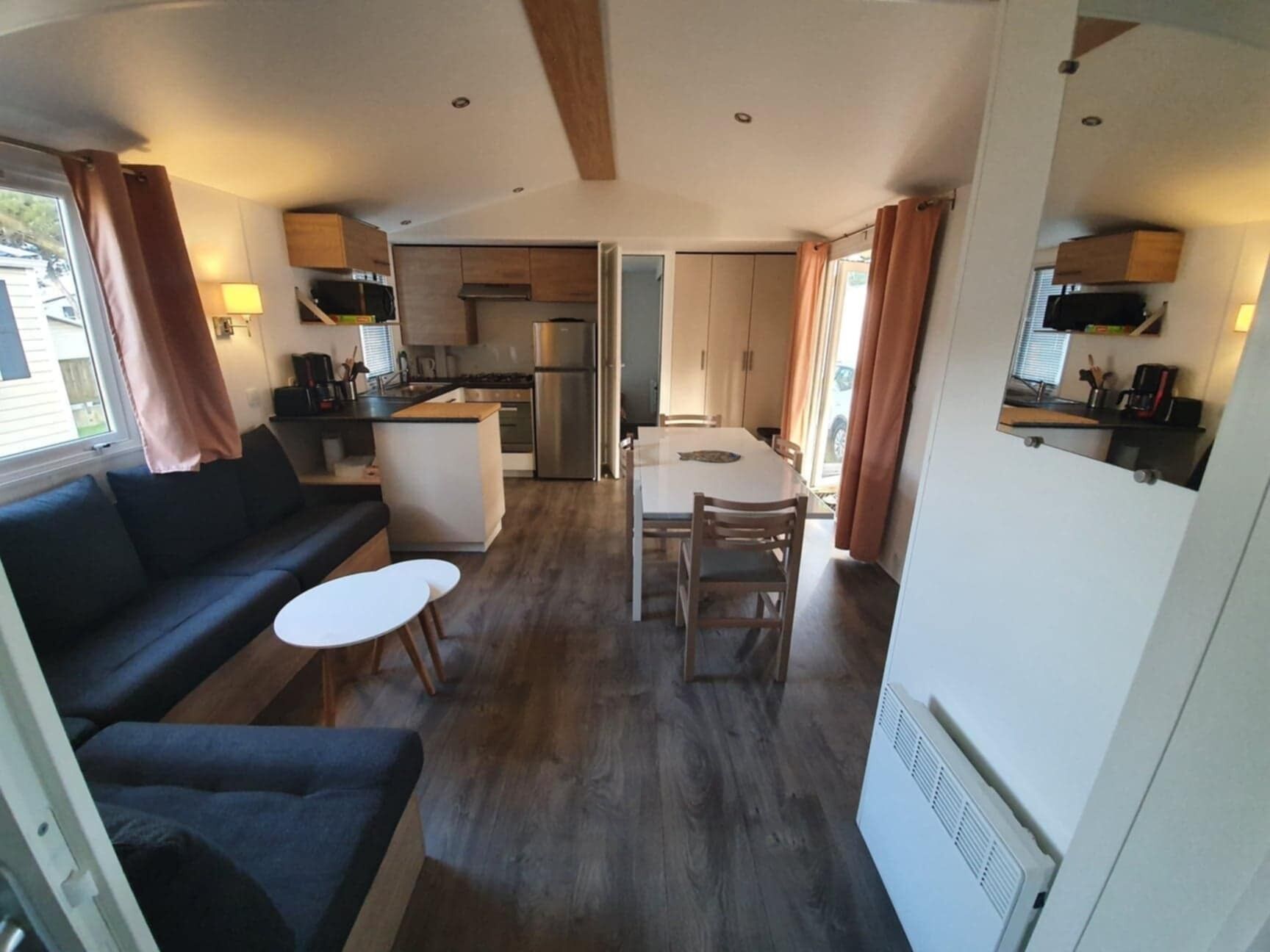 Un espacio habitable compacto con sofá, una mesita, zona de comedor y kitchenette.