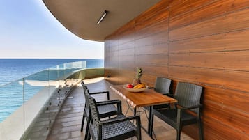 Un balcón con pared de madera, una mesa con sillas y un frutero.