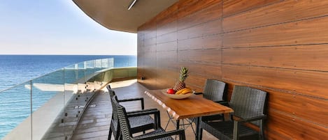 A balcony with a wooden wall, a table with chairs, and a fruit bowl.