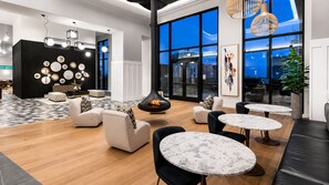 A modern lounge area with seating, tables, and artwork. - City Skyline Oasis | 2BR Highrise | Year-Round Pool |Balcony | State Farm Arena (Atlanta)