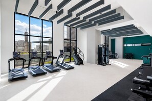 A modern gym with treadmills, weight machines, and a view of the city. - City Skyline Oasis | 2BR Highrise | Year-Round Pool |Balcony | State Farm Arena (Atlanta)
