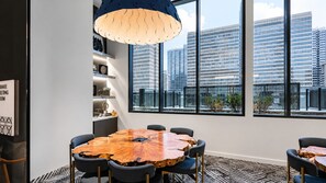 A modern meeting room with a large wooden table, black chairs, and a city view through large windows. - City Skyline Oasis | 2BR Highrise | Year-Round Pool |Balcony | State Farm Arena (Atlanta)