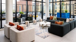A modern lounge area with sofas, chairs, and a coffee table, large windows offering city views. - City Skyline Oasis | 2BR Highrise | Year-Round Pool |Balcony | State Farm Arena (Atlanta)